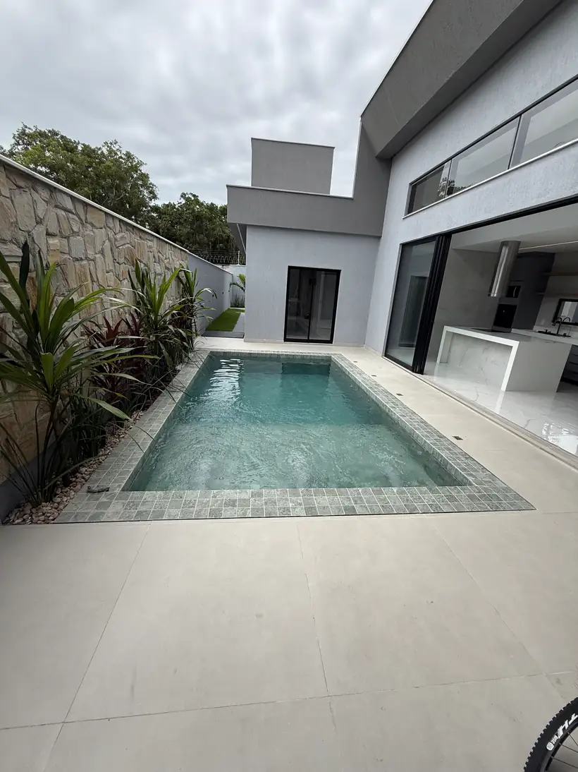 Piscina com borda em pedra e cozinha aberta para a área externa